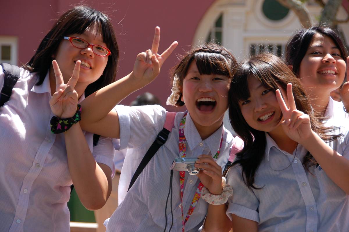 Three girls in Malaysia holding up peace signs.